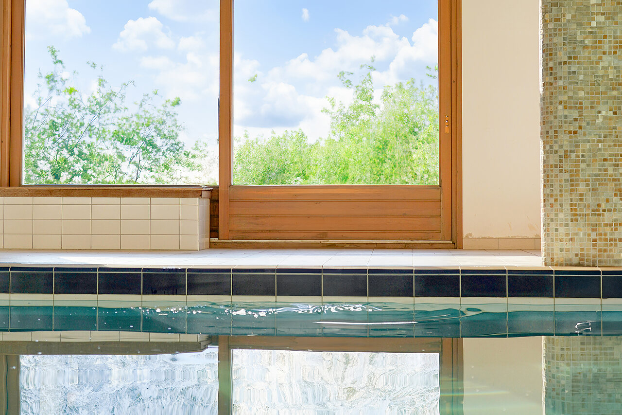 Bord de piscine int�rieure avec grandes baies vitr�es sur la nature au camping CLICOCHIC Alpes Lodges � Pralognan la Vanoise (73).