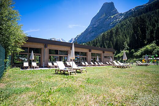 Bâtiment moderne, chaises et vue montagne au camping CLICOCHIC Alpes Lodges.