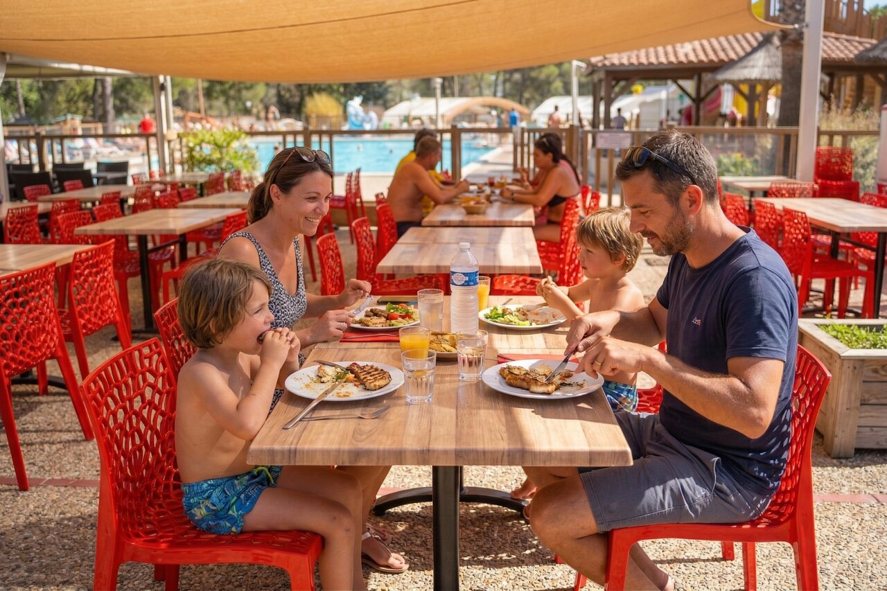 Famille d�jeunant au restaurant ext�rieur pr�s de la piscine au camping CAPFUN Arbois du Castellet � LE CASTELLET (83).