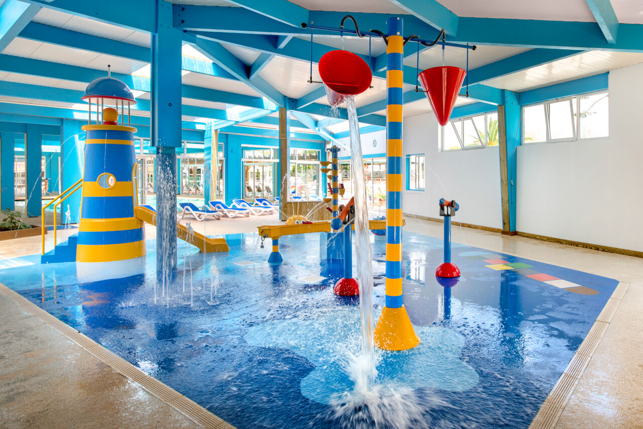Aire de jeux aquatique int�rieure avec toboggan phare et seaux verseurs au camping LIBRANOO Naturiste Arnaoutchot � Veille-Saint-Girons, Landes, France.