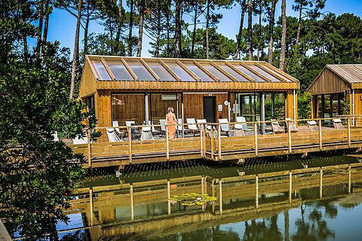Bâtiment spa en bois avec terrasse sur l'eau au camping LIBRANOO Naturiste Arnaoutchot à Veille-Saint-Girons, Landes, France.
