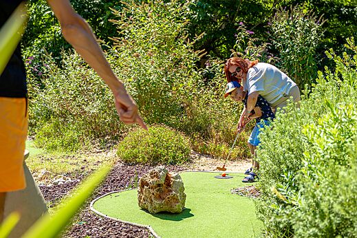 Enfant et adulte jouant au mini-golf sur le parcours au camping CAPFUN Aubr�des � Puget sur Argens (83).