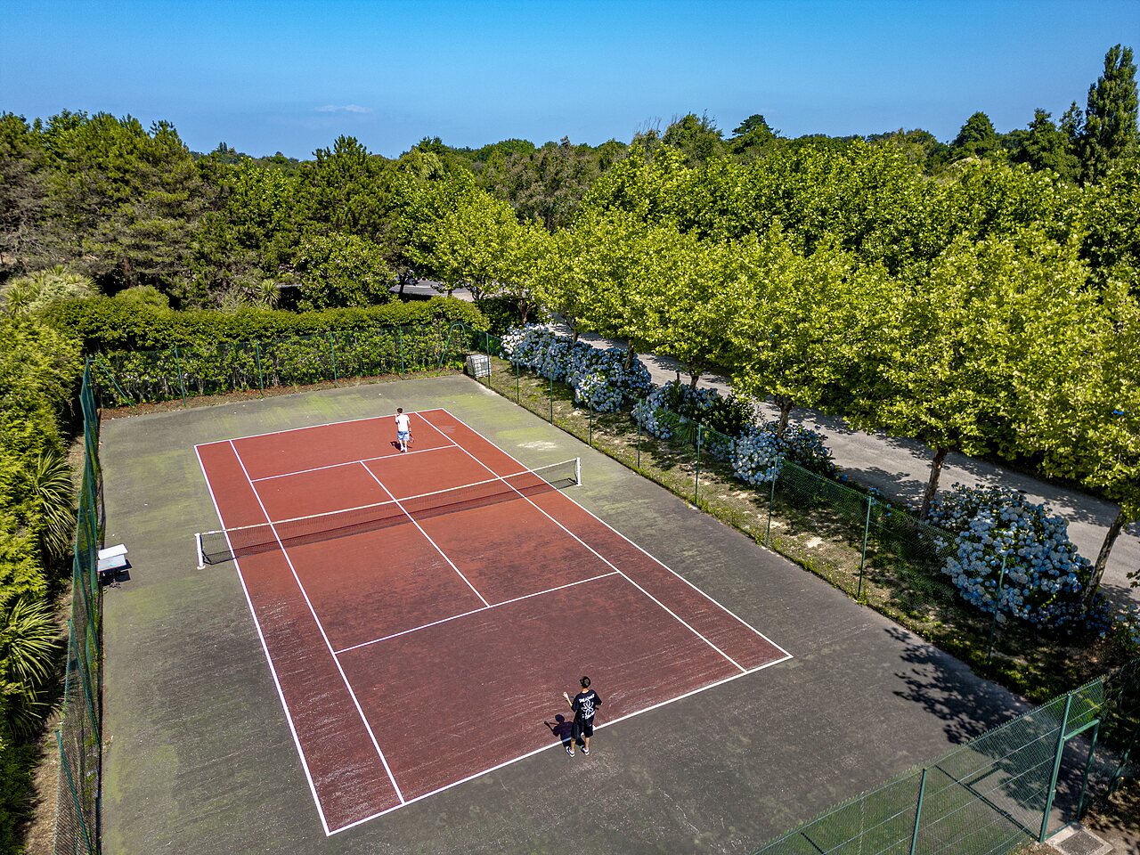 Court de tennis ext�rieur avec joueurs au camping CLICOCHIC Baie de Douarnenez (29).