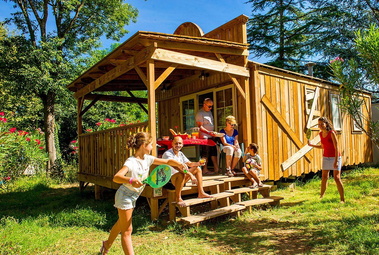 Famille profitant d'un chalet en bois et jouant au camping CAPFUN Bastide � N�mes (30).