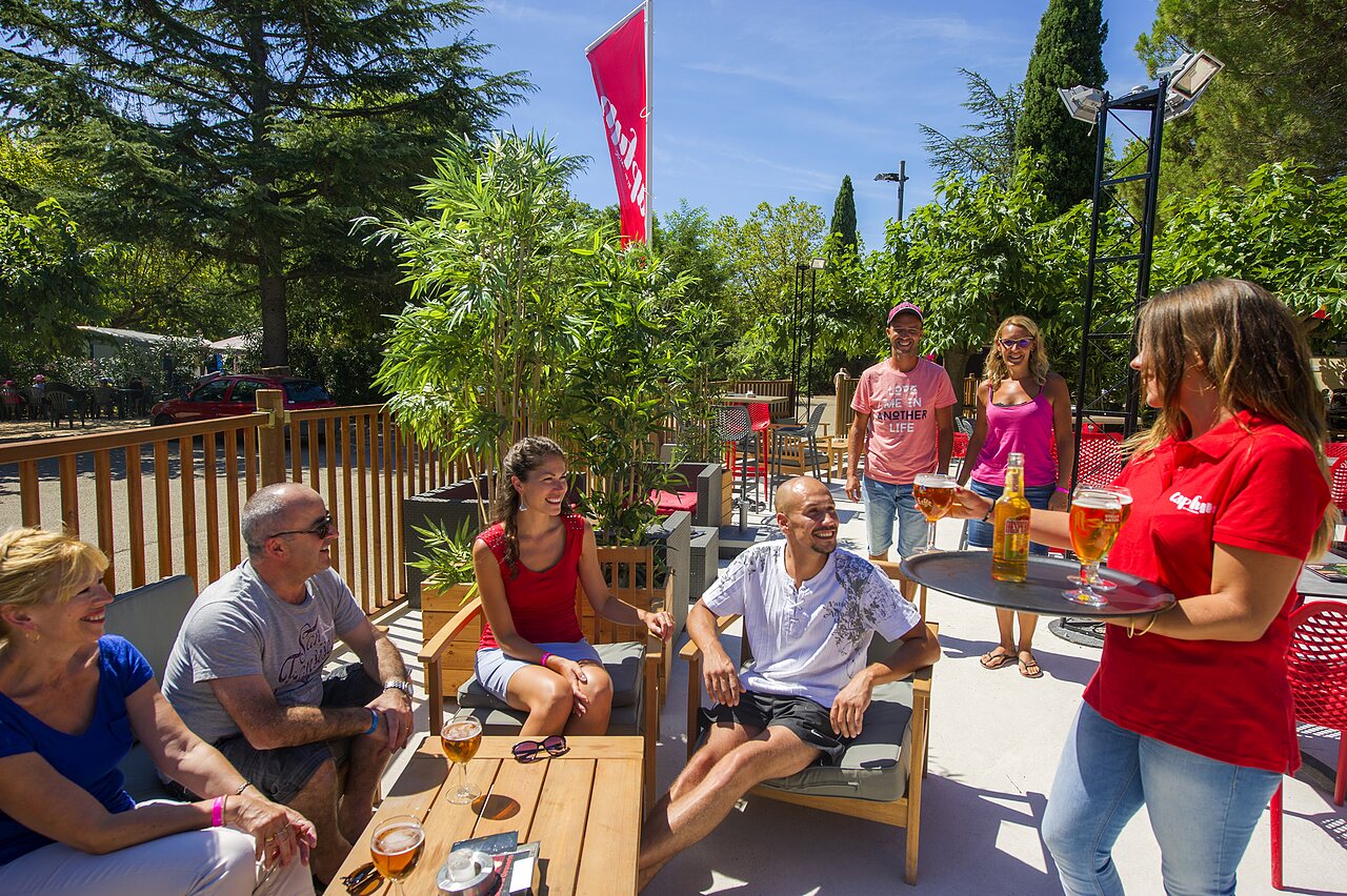 Clients profitant de boissons sur la terrasse du bar au camping CAPFUN Bastide � N�mes (30).