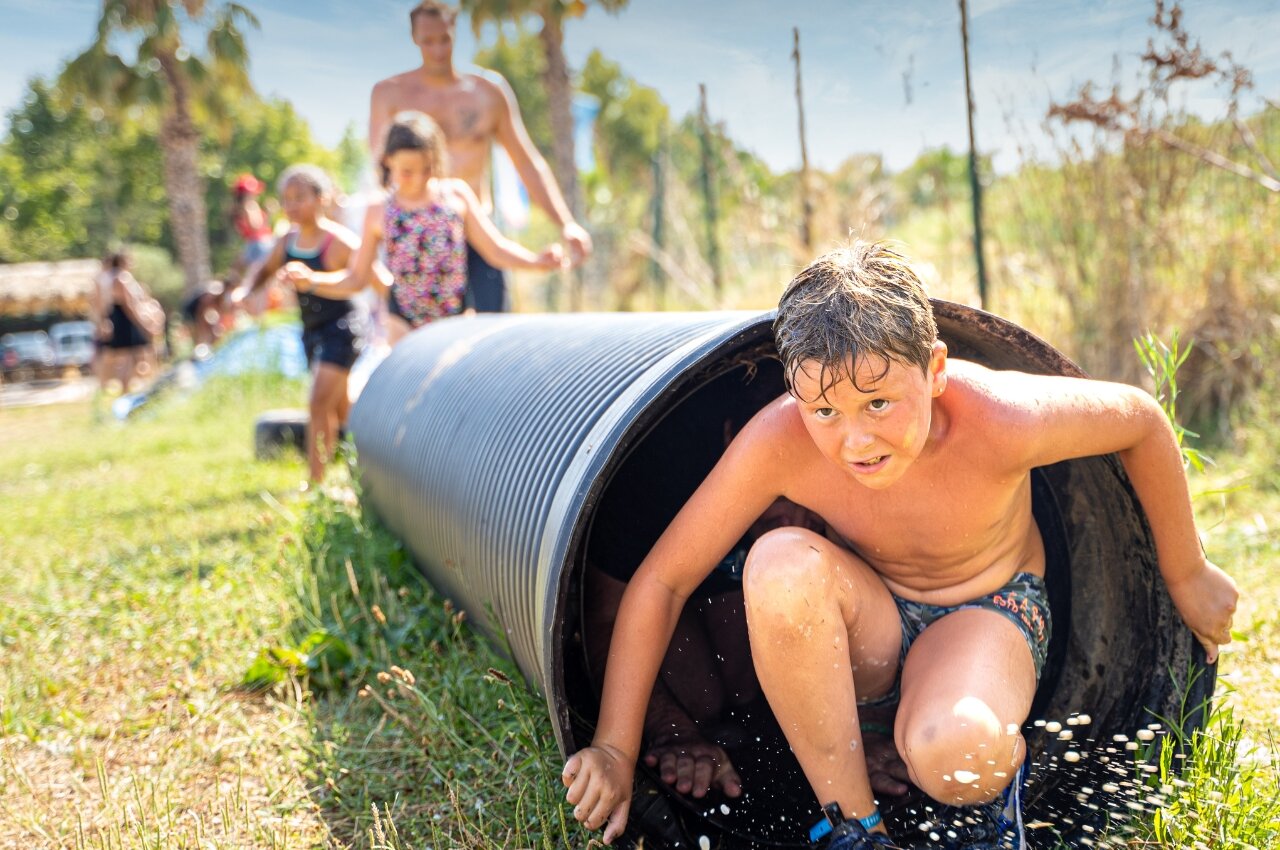 Enfant sortant d'un tunnel aquatique, jeux d'eau au camping CAPFUN Beauregard � MORNAS (84).