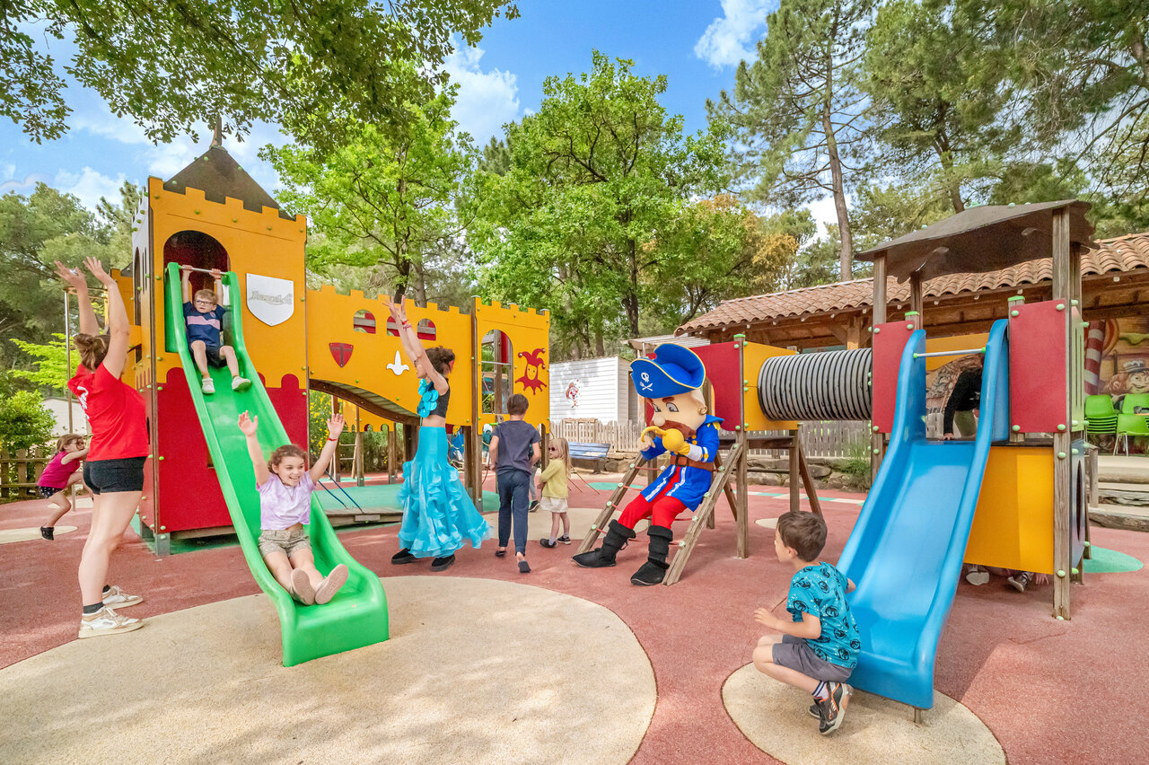 Aire de jeux avec toboggans, enfants et mascotte au camping CAPFUN Beauregard � MORNAS (84).