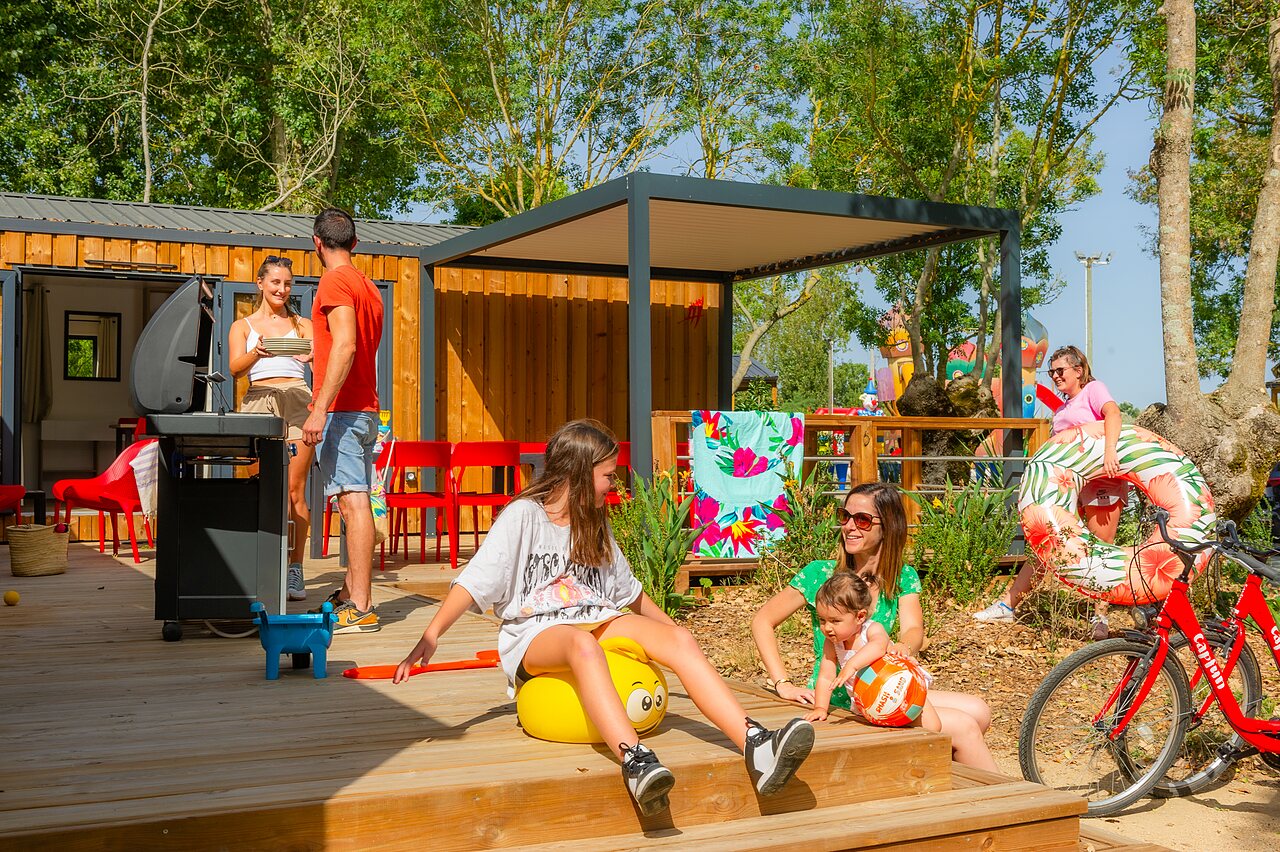 Famille profitant terrasse mobil-home, barbecue, bou�e, camping CAPFUN Bel Air (85).