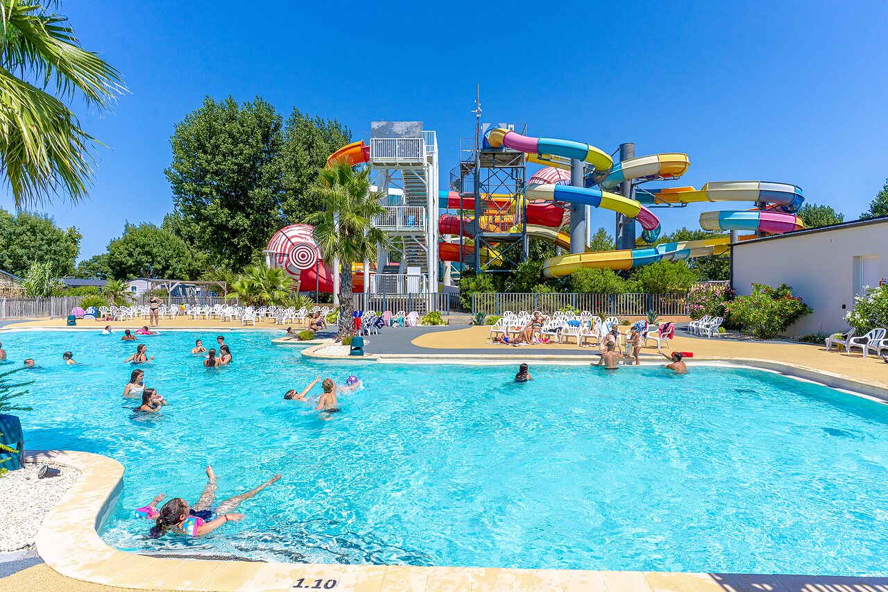 Piscine ext�rieure avec toboggans aquatiques color�s et baigneurs au camping CAPFUN Bel Air � Aiguillon sur Mer (85).