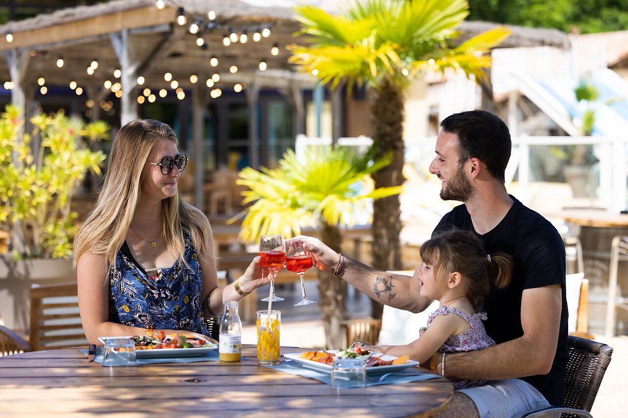 Famille heureuse d�nant sur la terrasse du restaurant au camping CLICOCHIC Bimbo � BISCARROSSE (40).