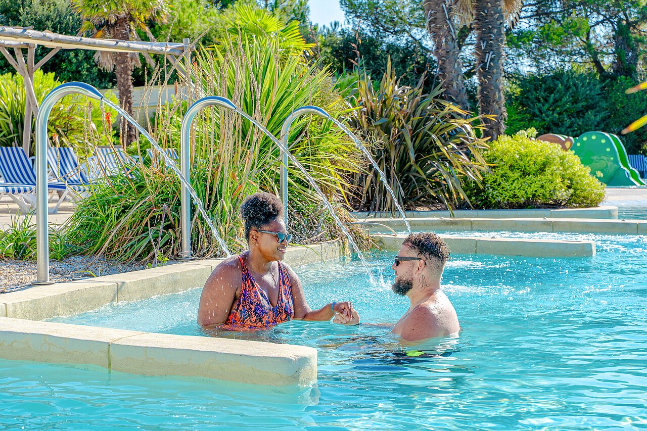 Couple se d�tendant dans la piscine avec jets d'eau au camping VAGUES OCEANES Blancs Ch�nes � LA TRANCHE SUR MER (85).
