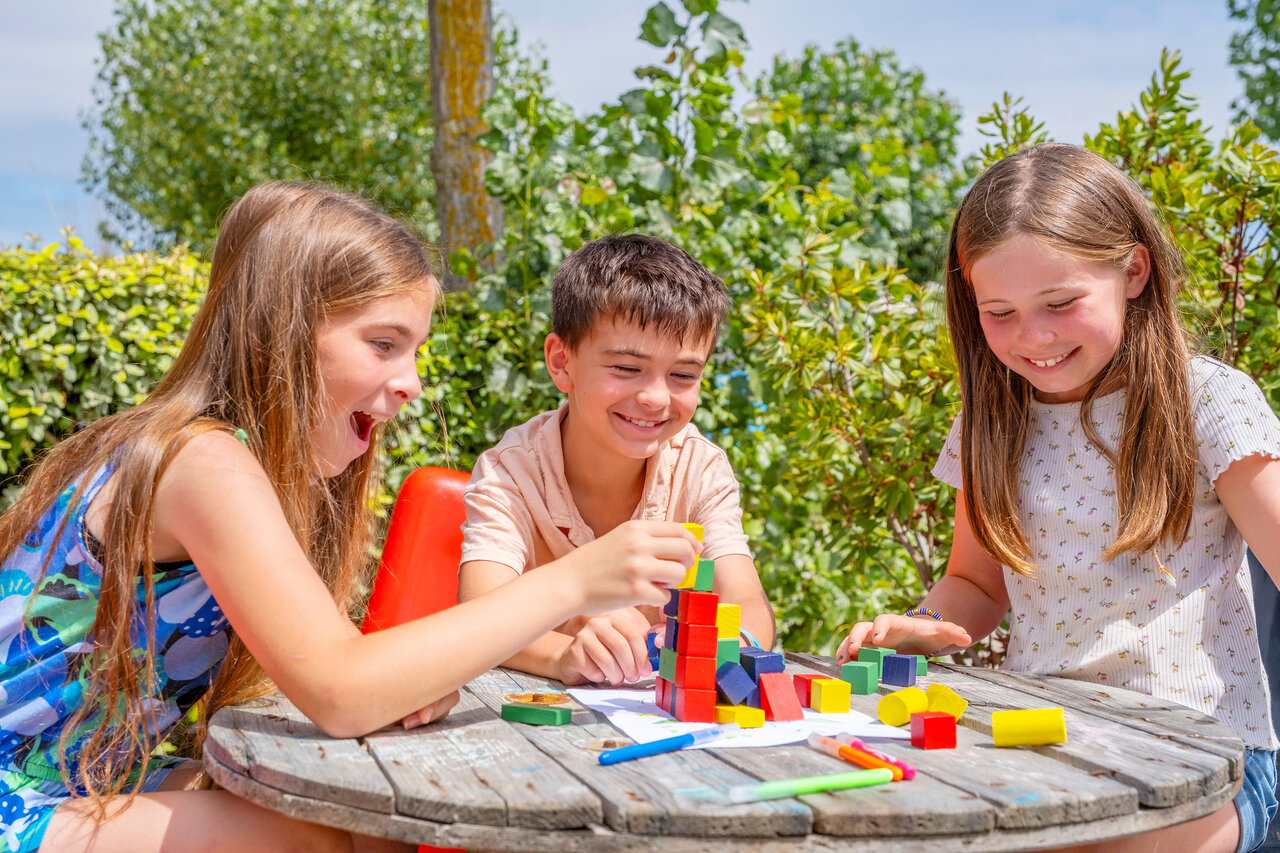 Enfants souriants jouant avec des blocs color�s au camping VAGUES OCEANES Bois Joly.