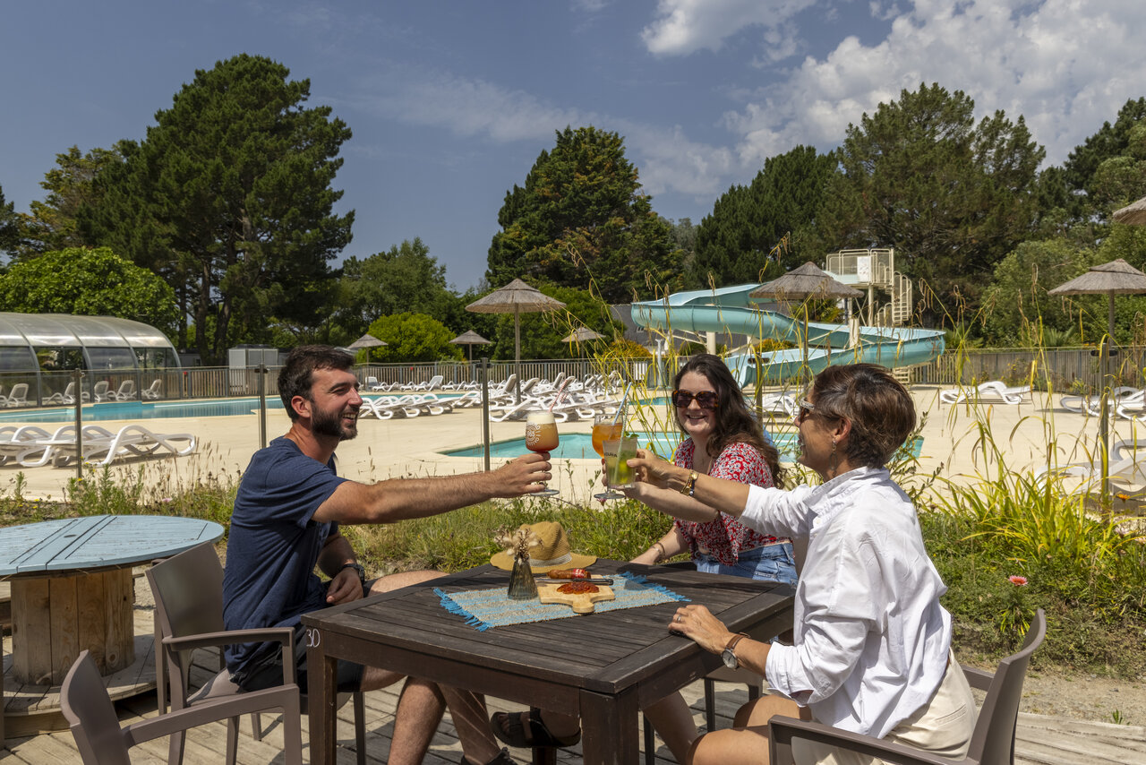 Vacanciers trinquant au bar, piscine ext�rieure et toboggan au camping CLICOCHIC Bord�n�o Belle-�le-en-Mer � Le Palais (56).