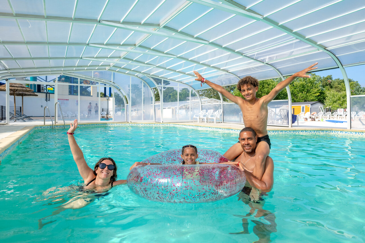 Famille souriante profitant de la piscine couverte au camping VAGUES OCEANES Boudigau � LABENNE OCEAN (40).