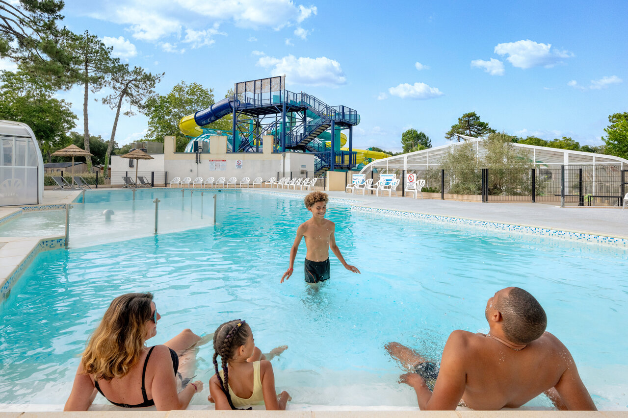 Famille s'amusant dans la piscine ext�rieure avec toboggans au camping VAGUES OCEANES Boudigau � LABENNE OCEAN (40).