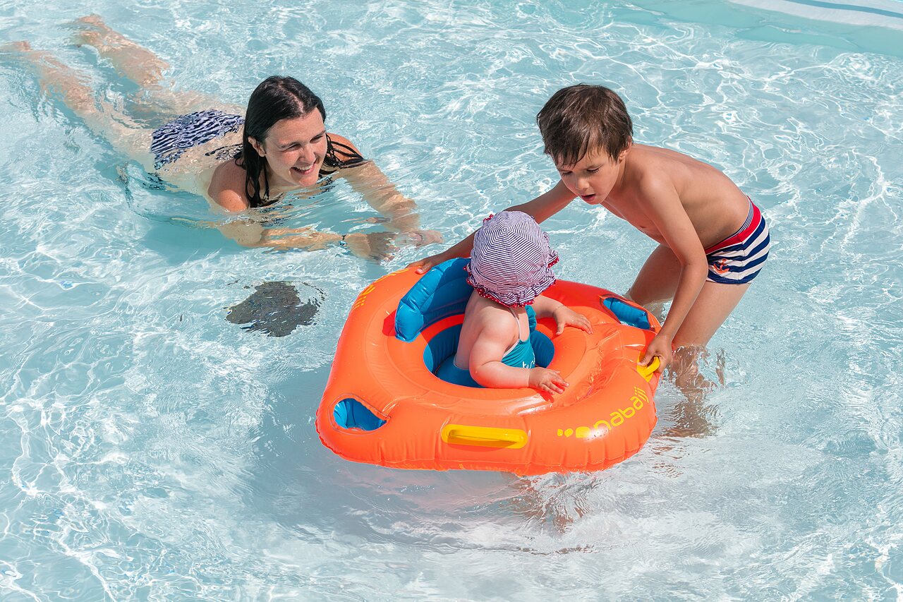 Famille avec b�b� dans bou�e, piscine ext�rieure au camping CLICOCHIC Brandais.