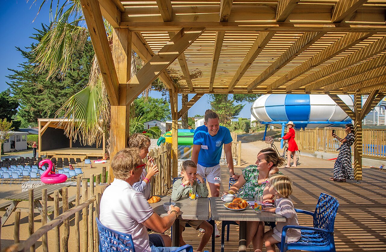 Famille d�jeunant sous pergola, animateur, sc�ne, toboggan au camping CLICOCHIC Brandais � Brem sur Mer (85).