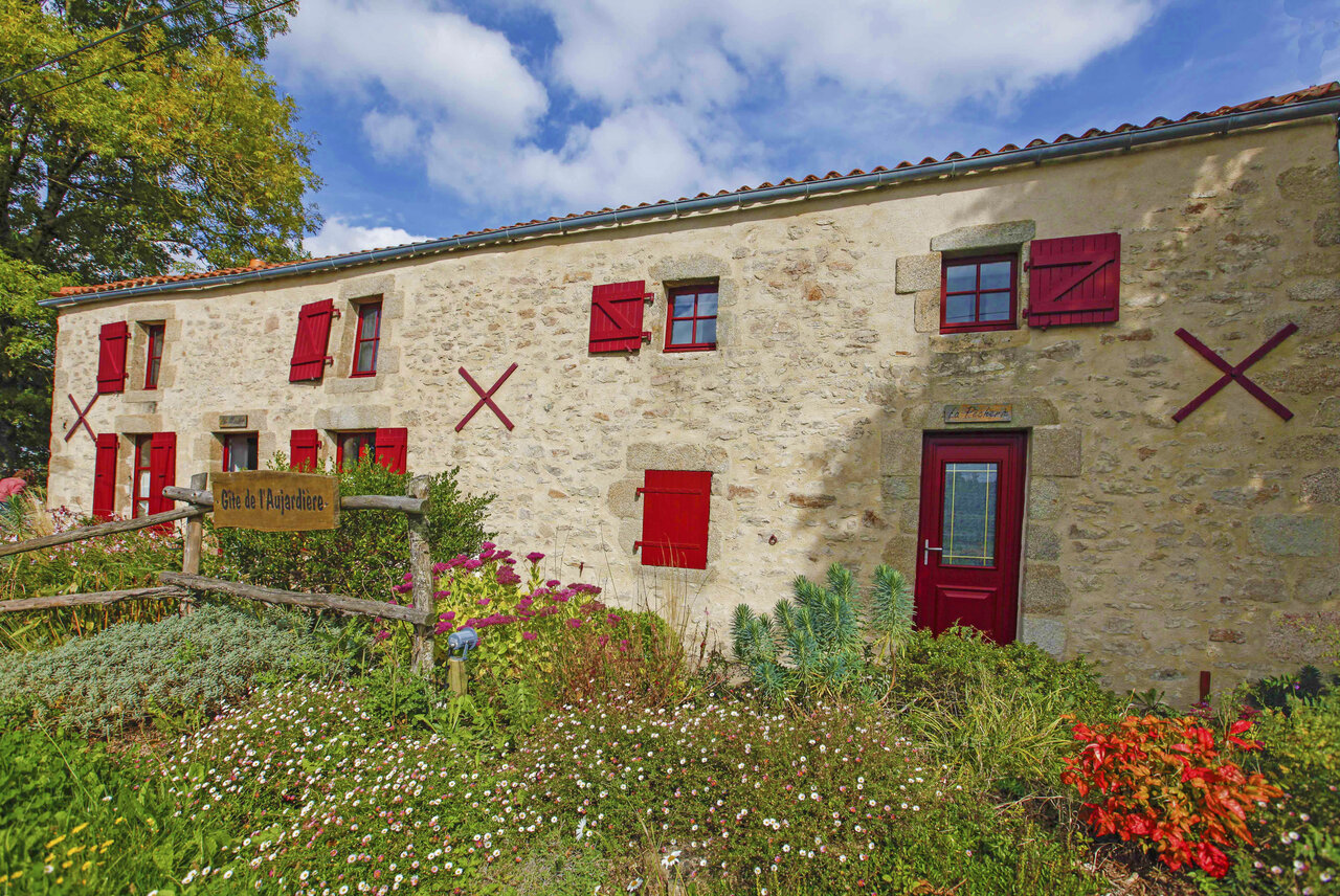 G�te en pierre, volets rouges, jardin fleuri au camping CAPFUN Breteche, Les Epesses.