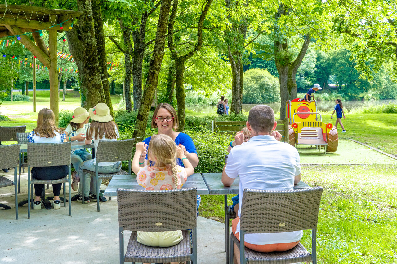 Familles sur terrasse restaurant, enfants jouant pr�s d'un lac, camping CAPFUN Breteche.
