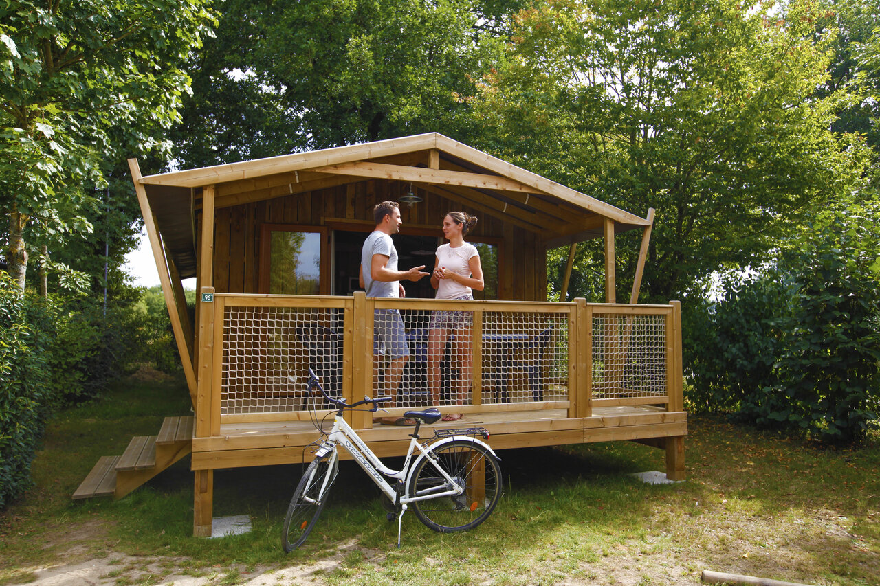 Chalet en bois, couple sur terrasse, v�lo au CAPFUN Breteche Les Epesses (85).