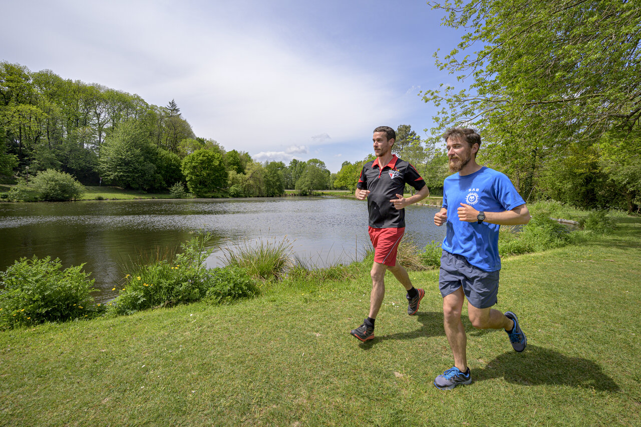 Deux hommes font du jogging au bord d'un lac, nature verdoyante, au camping CAPFUN Breteche � Les Epesses (85).