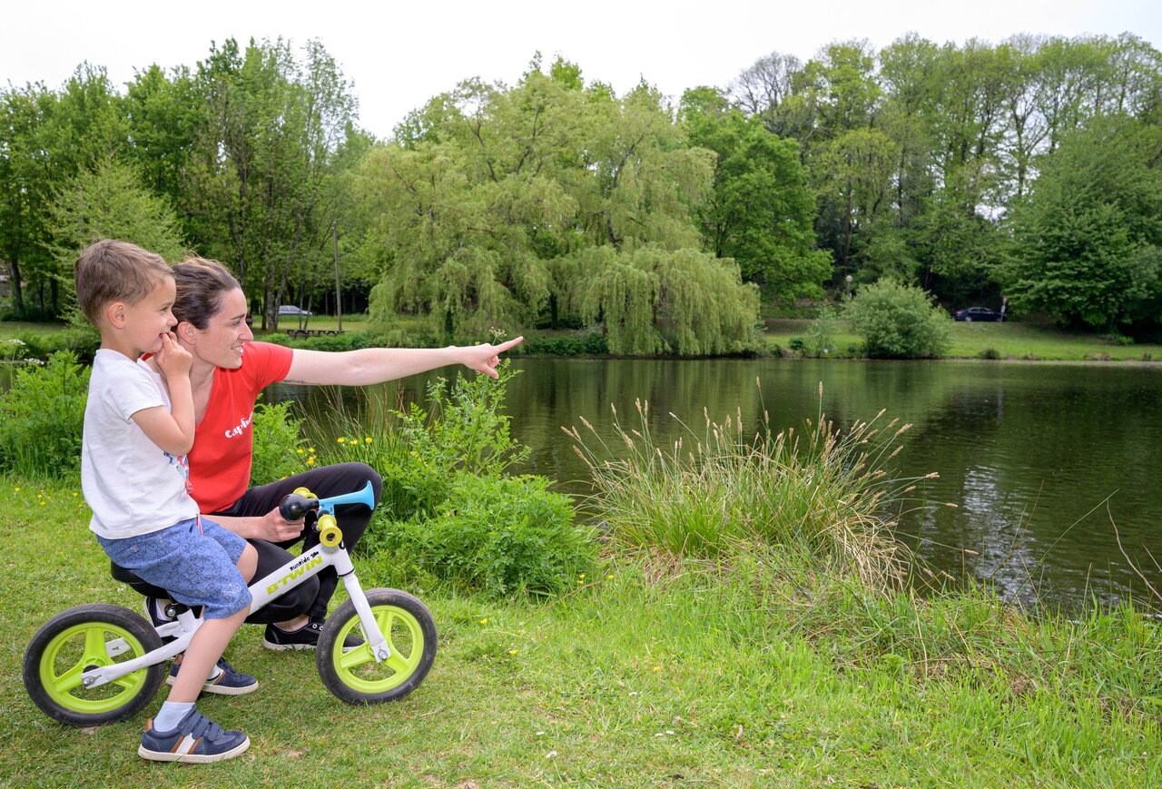 Enfant sur draisienne et femme pointant le lac, nature au camping CAPFUN Breteche � Les Epesses (85).