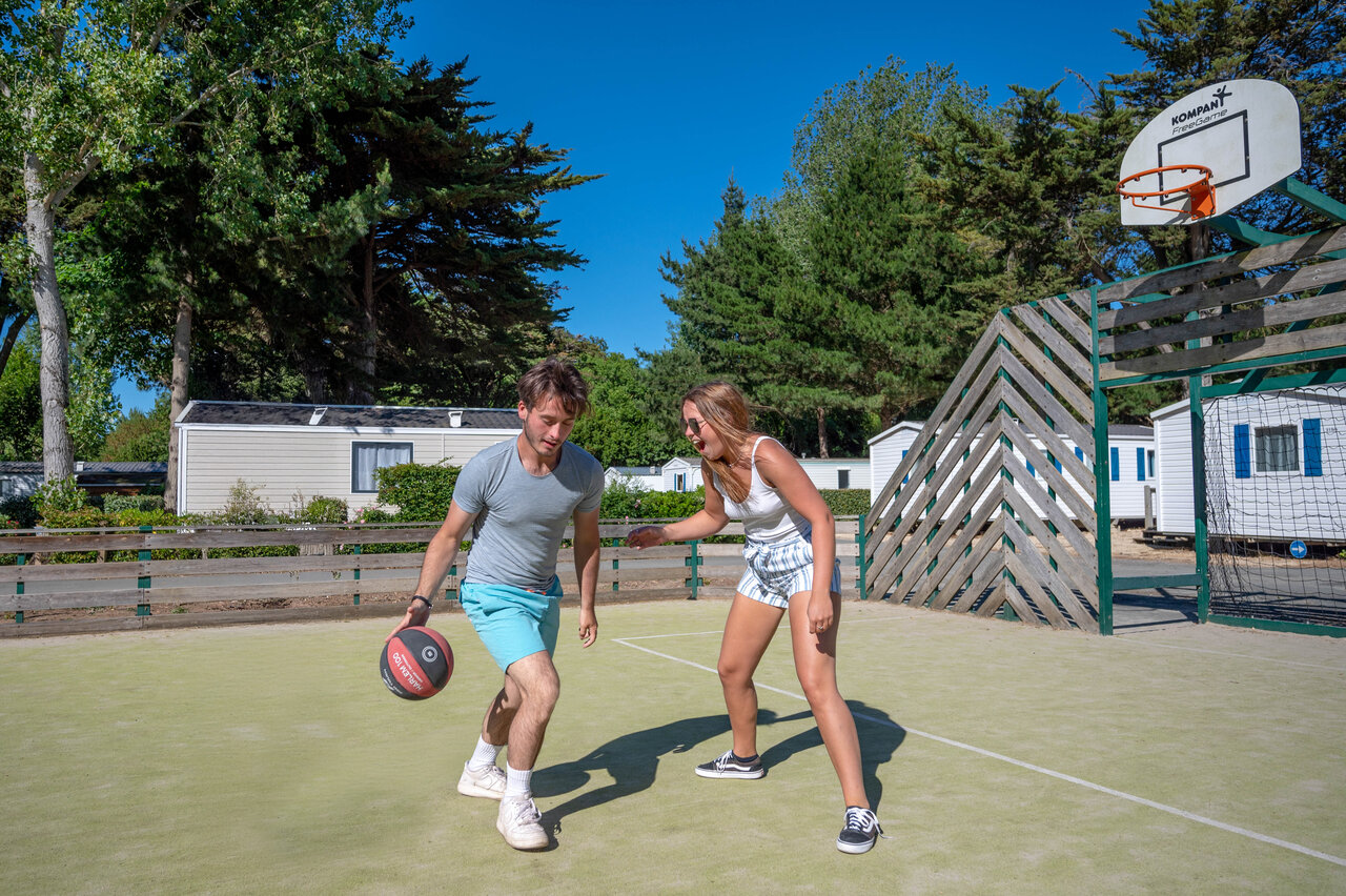 Couple jouant au basketball sur terrain multisport au camping CLICOCHIC Cabanes d'Ol�ron.