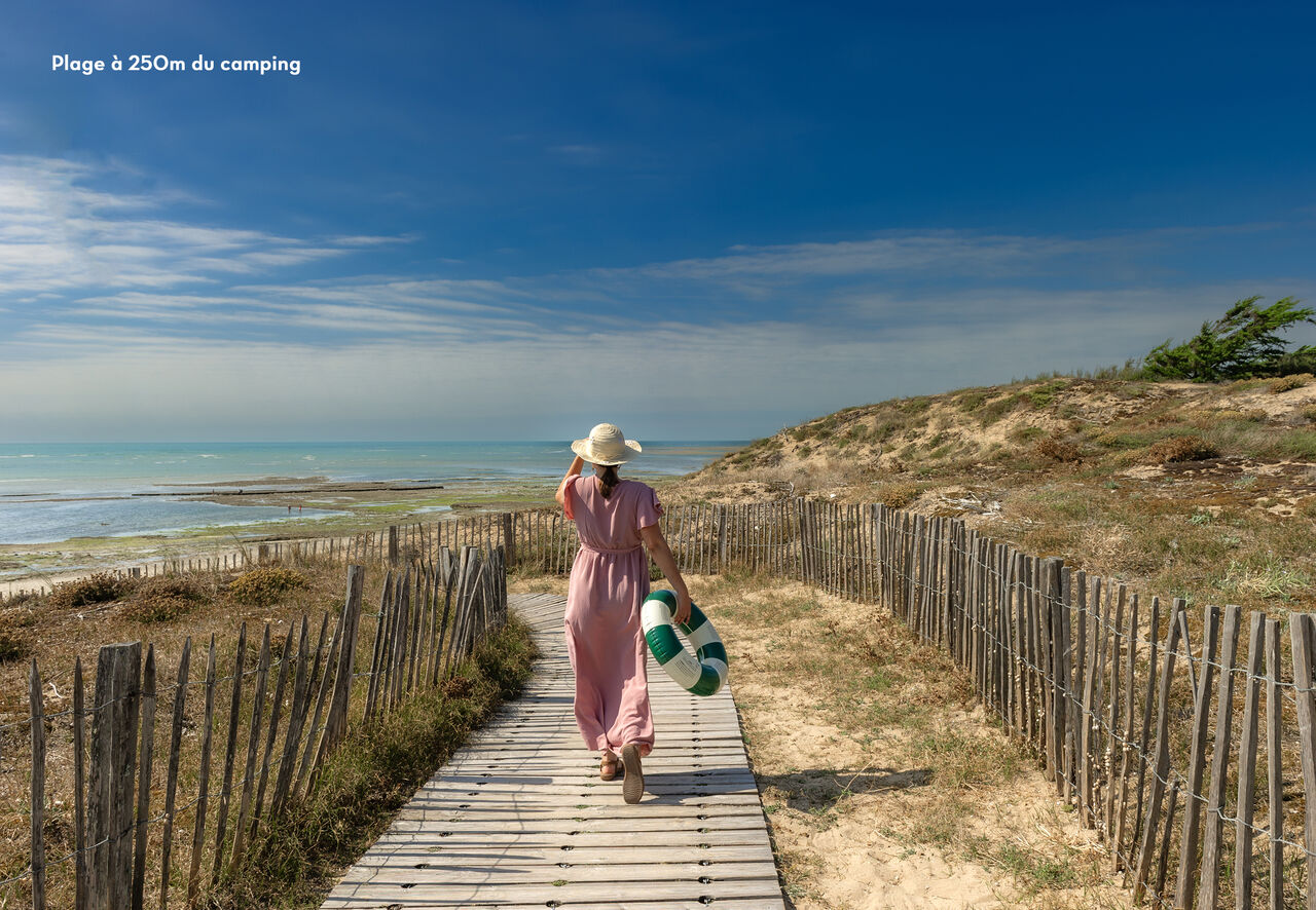 Femme marchant sur une passerelle en bois vers la plage au camping CLICOCHIC Camp du Soleil � Ars-en-R� (17).