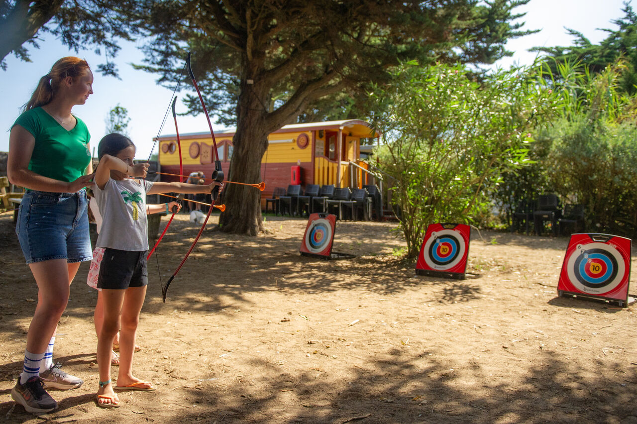 Enfant pratiquant le tir � l'arc avec un animateur au camping CAPFUN Cenic � Ars-en-R�.