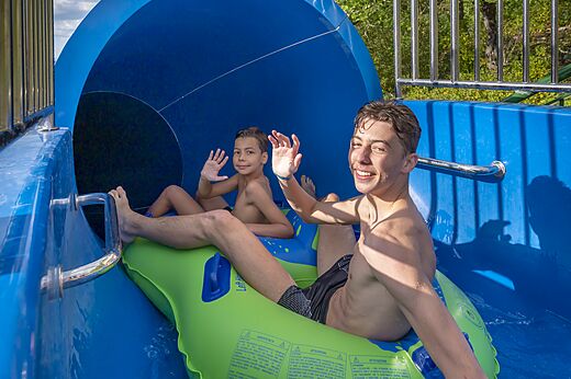 Enfants sur bou�e dans toboggan aquatique au camping CLICOCHIC Ch�teau de Boisson.