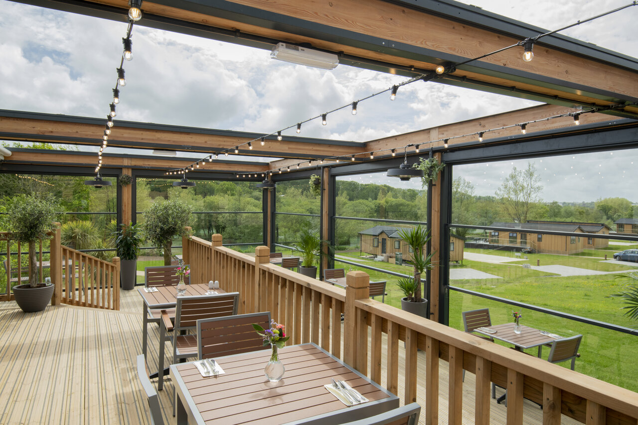 Terrasse de restaurant ext�rieure avec tables, vue sur lodges, CAPFUN UK Clawford Lakes.