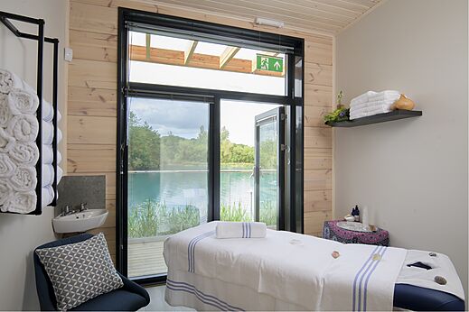 Table de massage dans une salle de spa avec vue sur le lac au camping CAPFUN UK Clawford Lakes à Clawton, Holsworthy.