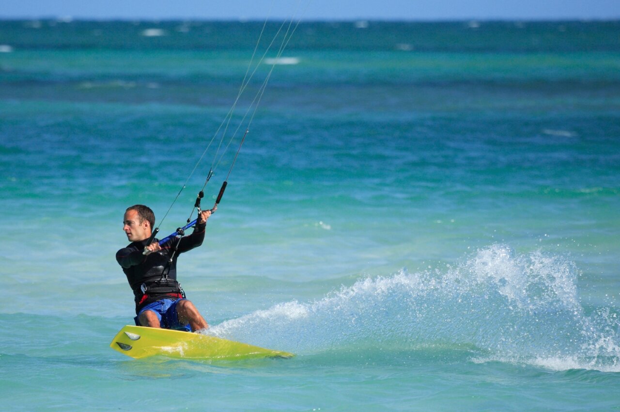 Homme pratiquant le kitesurf sur l'eau turquoise, �claboussures dynamiques au camping CAPFUN C�te Vermeille : Cabane dans les airs � Port La Nouvelle (11).