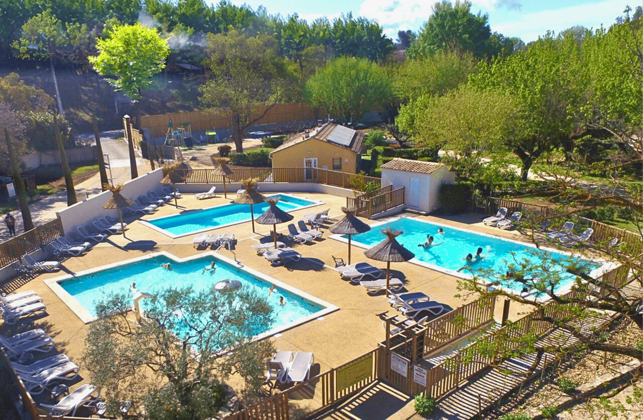 Complexe aquatique avec plusieurs piscines, transats et parasols au camping CLICOCHIC Couteli�re � Lagnes (84).
