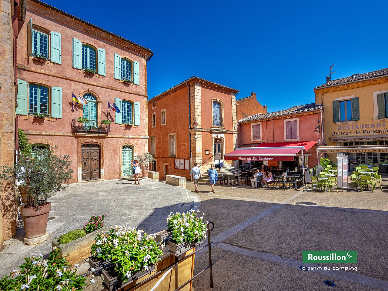 Place centrale du village de Roussillon, maisons color�es et restaurant en Provence.