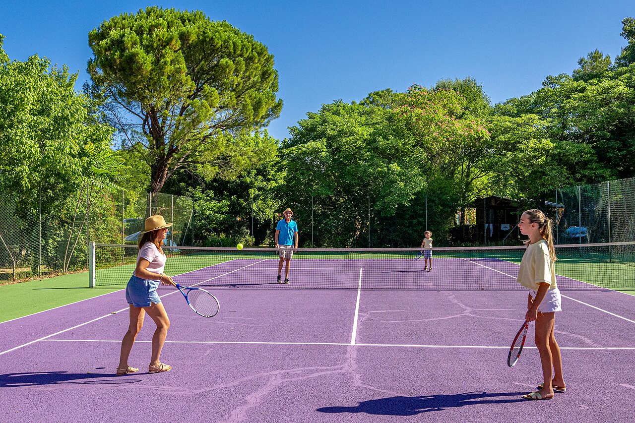 Famille jouant au tennis sur un court violet au camping CLICOCHIC Couteli�re � Lagnes (84).