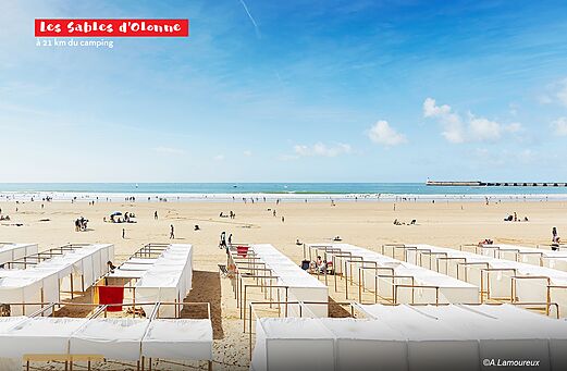 Grande plage de sable des Sables d'Olonne avec cabines de plage.