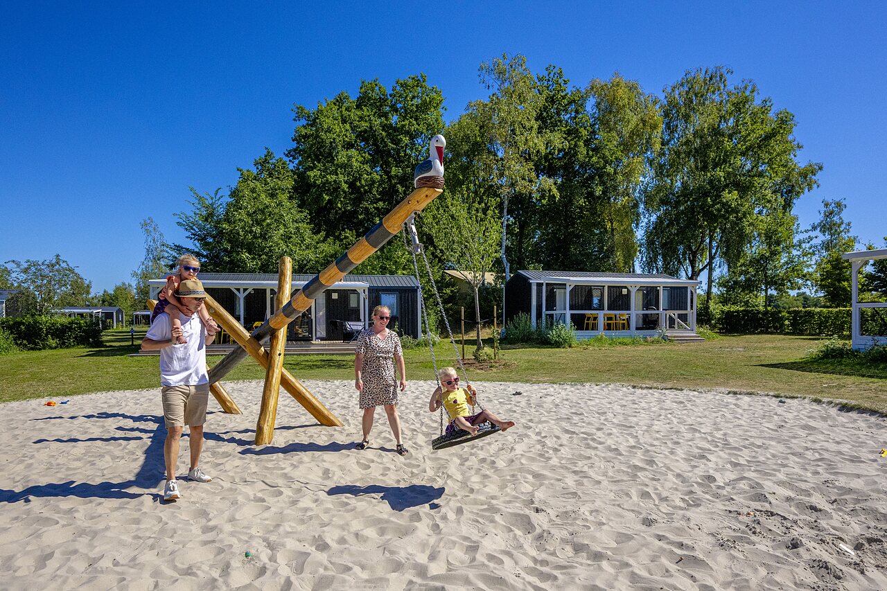 Aire de jeux sable avec balan�oire et famille, mobile homes au camping CAPFUN De Belten � Rheeze.