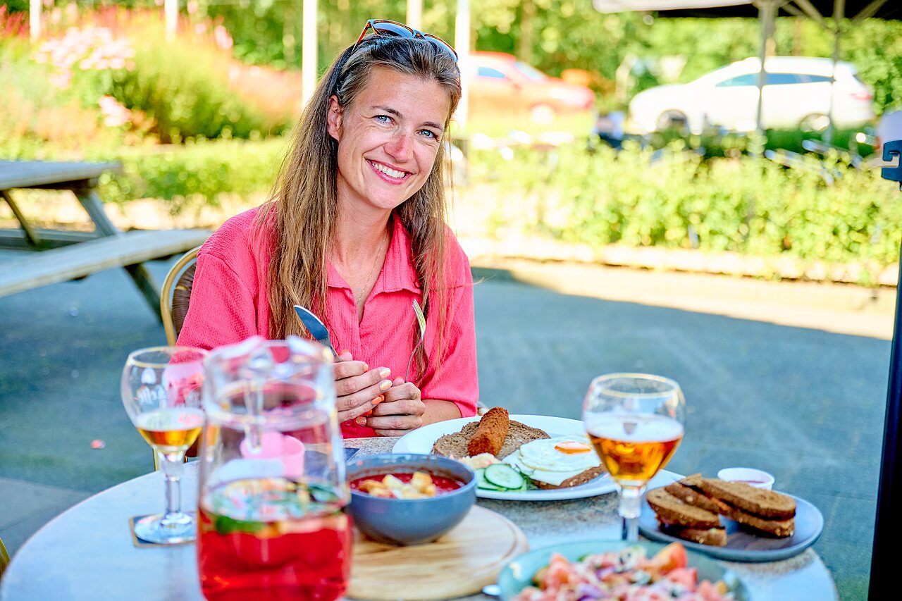 Femme souriante d�jeunant en terrasse au camping CAPFUN De Eikenhof � Paasloo/Oldemarkt.