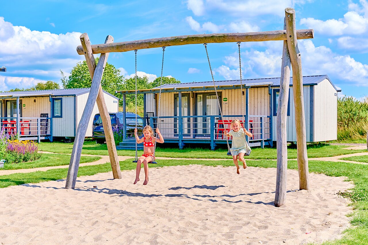 Enfants jouant sur balan�oires en bois, mobile homes au camping CAPFUN De Eikenhof � Paasloo/Oldemarkt.