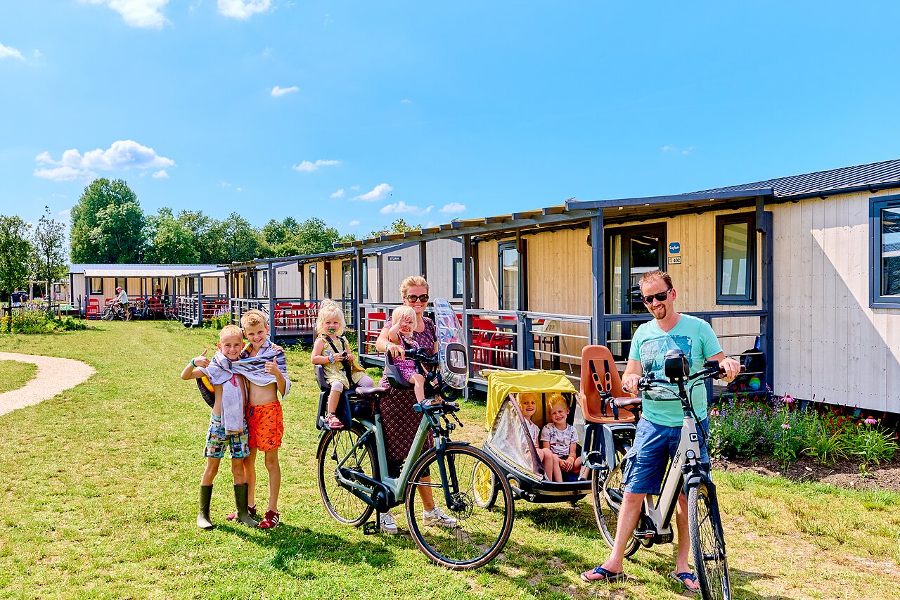 Famille � v�lo devant des mobil-homes modernes au camping CAPFUN De Eikenhof � Paasloo/Oldemarkt.