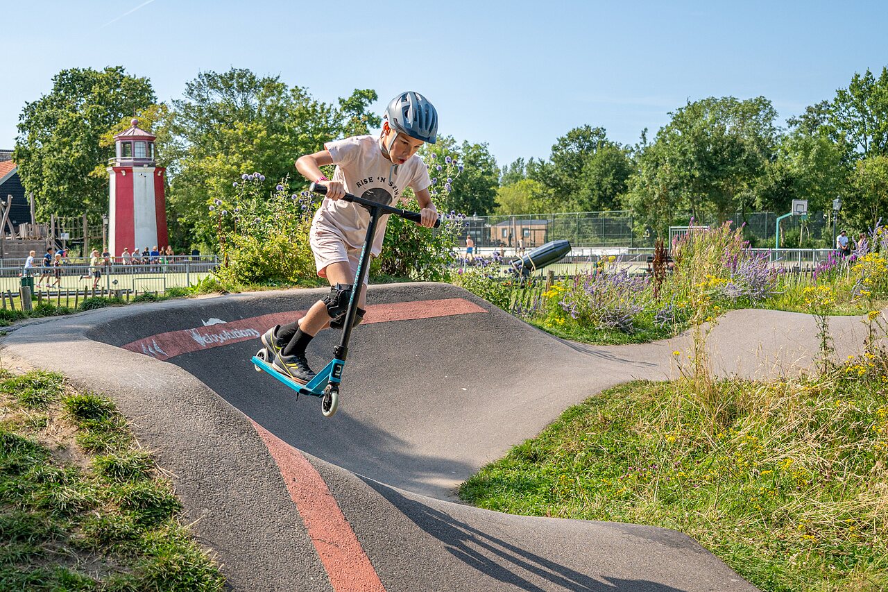 Enfant sur trottinette sur le pumptrack au camping CAPFUN De Pekelinge � Oostkapelle.