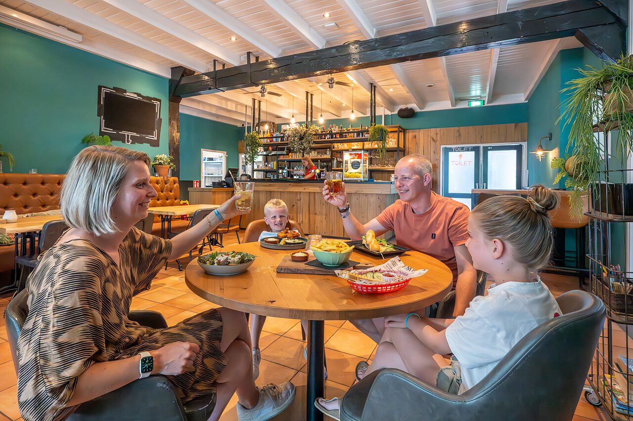 Famille souriante d�jeunant au restaurant du camping CAPFUN De Pekelinge � Oostkapelle.