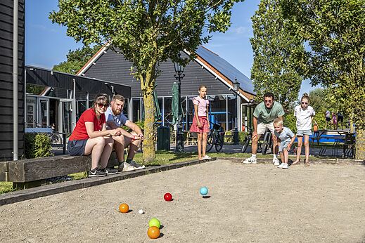 Famille jouant à la pétanque sur le terrain de jeux au camping CAPFUN De Pekelinge à Oostkapelle.