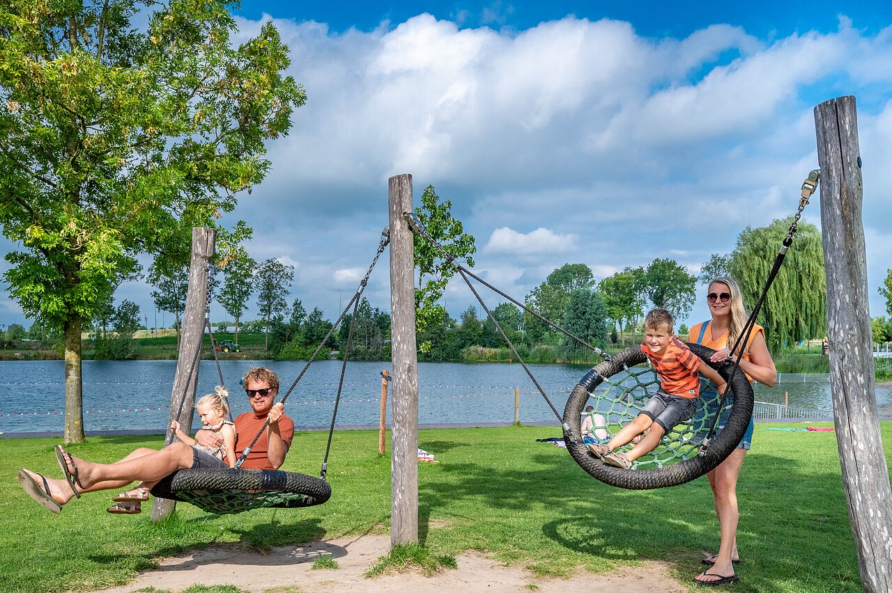 Aire de jeux avec balan�oires nid et lac au camping CAPFUN De Rotonde � Enspijk.