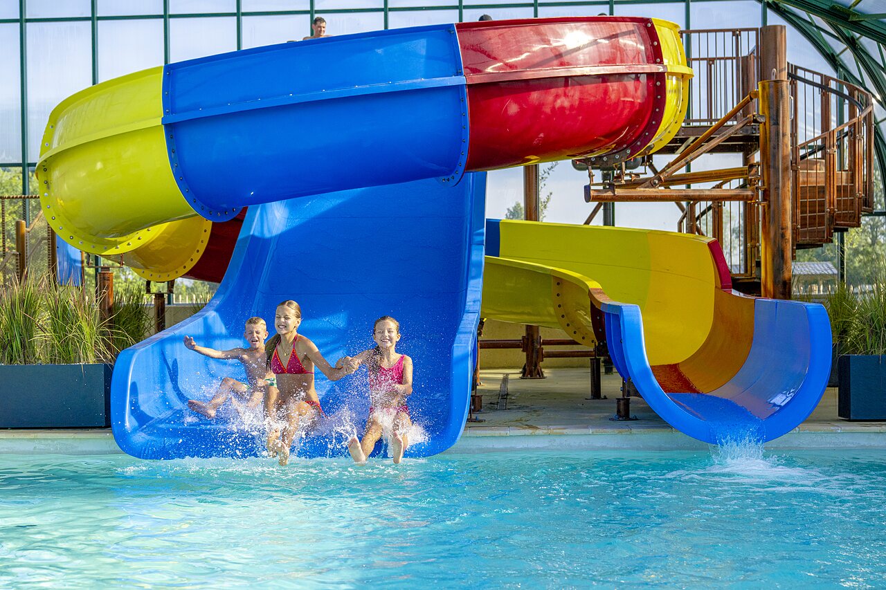 Toboggans aquatiques color�s et piscine couverte avec enfants et adultes au camping CAPFUN De Rotonde � Enspijk.