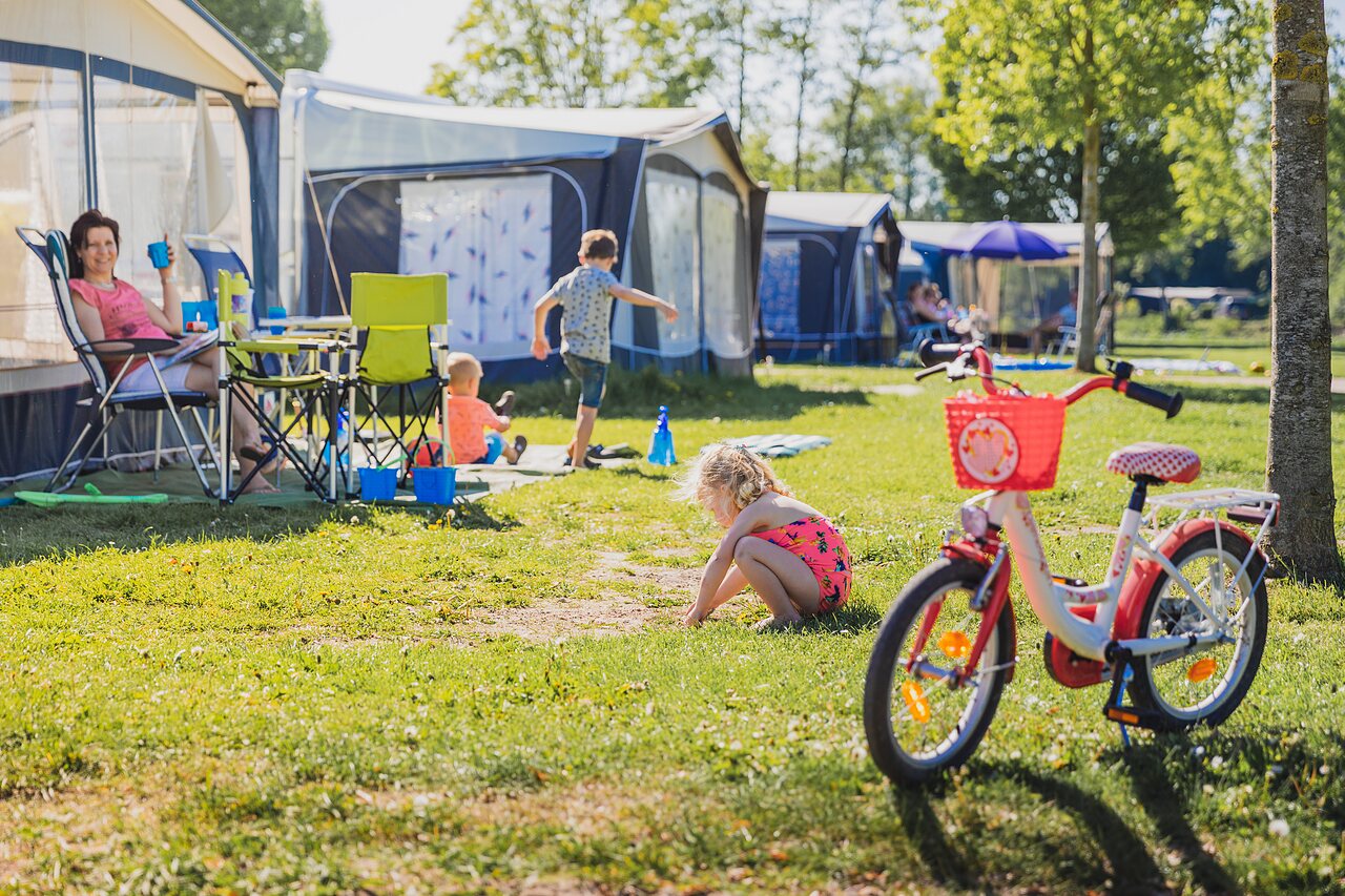 Famille se d�tendant sur un emplacement de camping avec tente et auvent au camping CAPFUN De Rotonde � Enspijk.