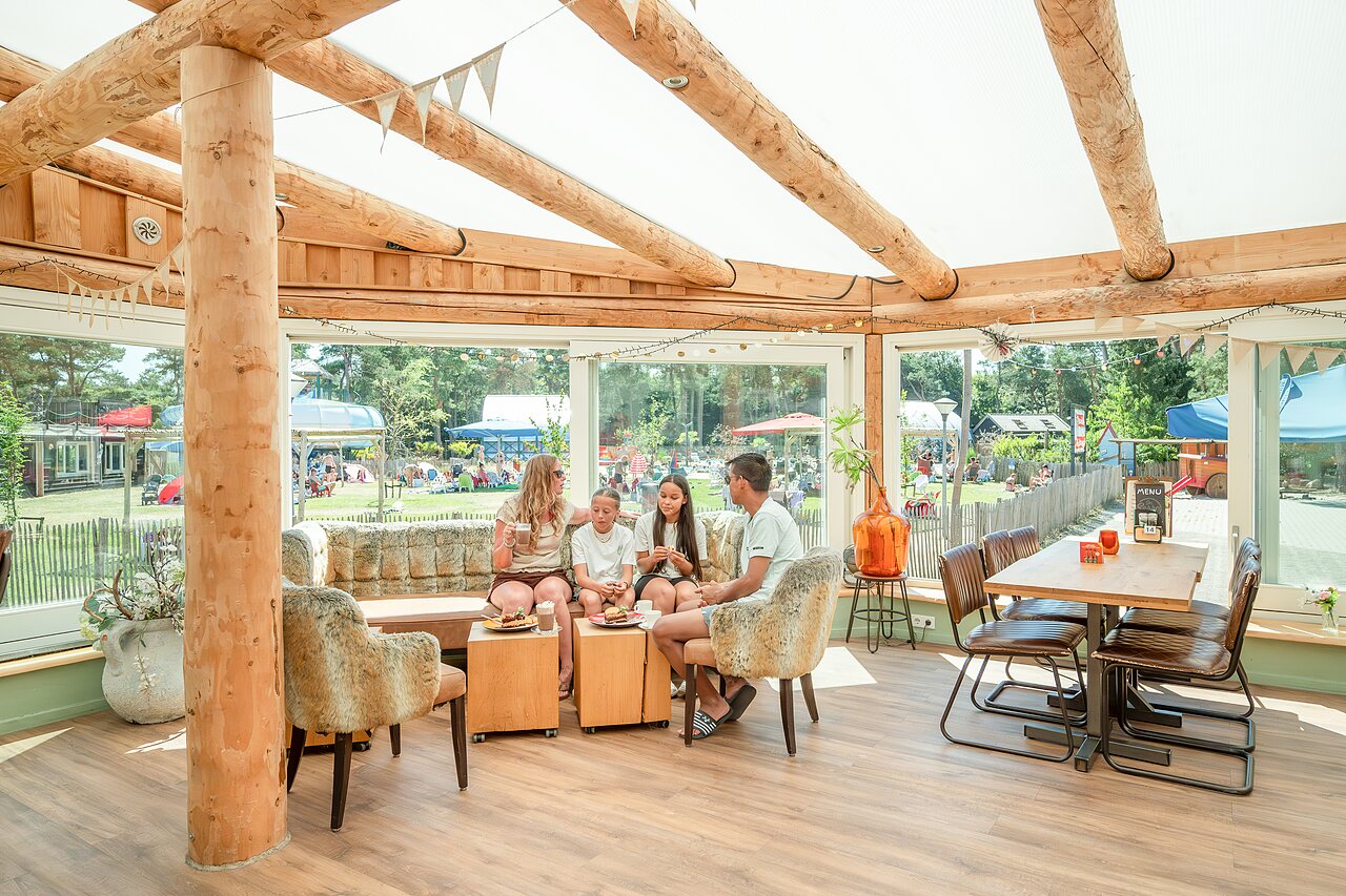 Famille relaxant dans l'espace restaurant/bar du camping CAPFUN De Scheepsbel � Doornspijk.