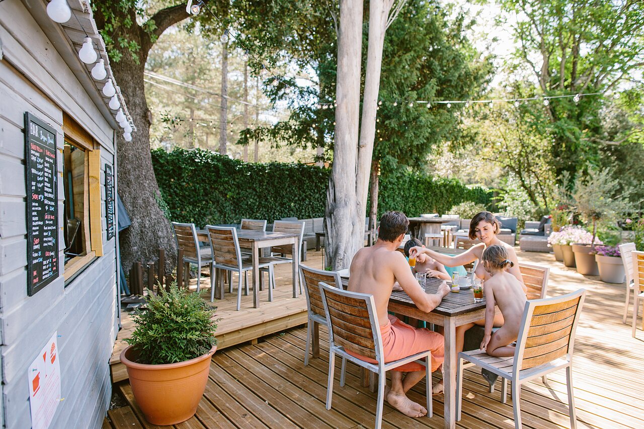 Famille naturiste d�jeunant en terrasse au bar du camping LIBRANOO Naturiste Belezy � B�doin (84).