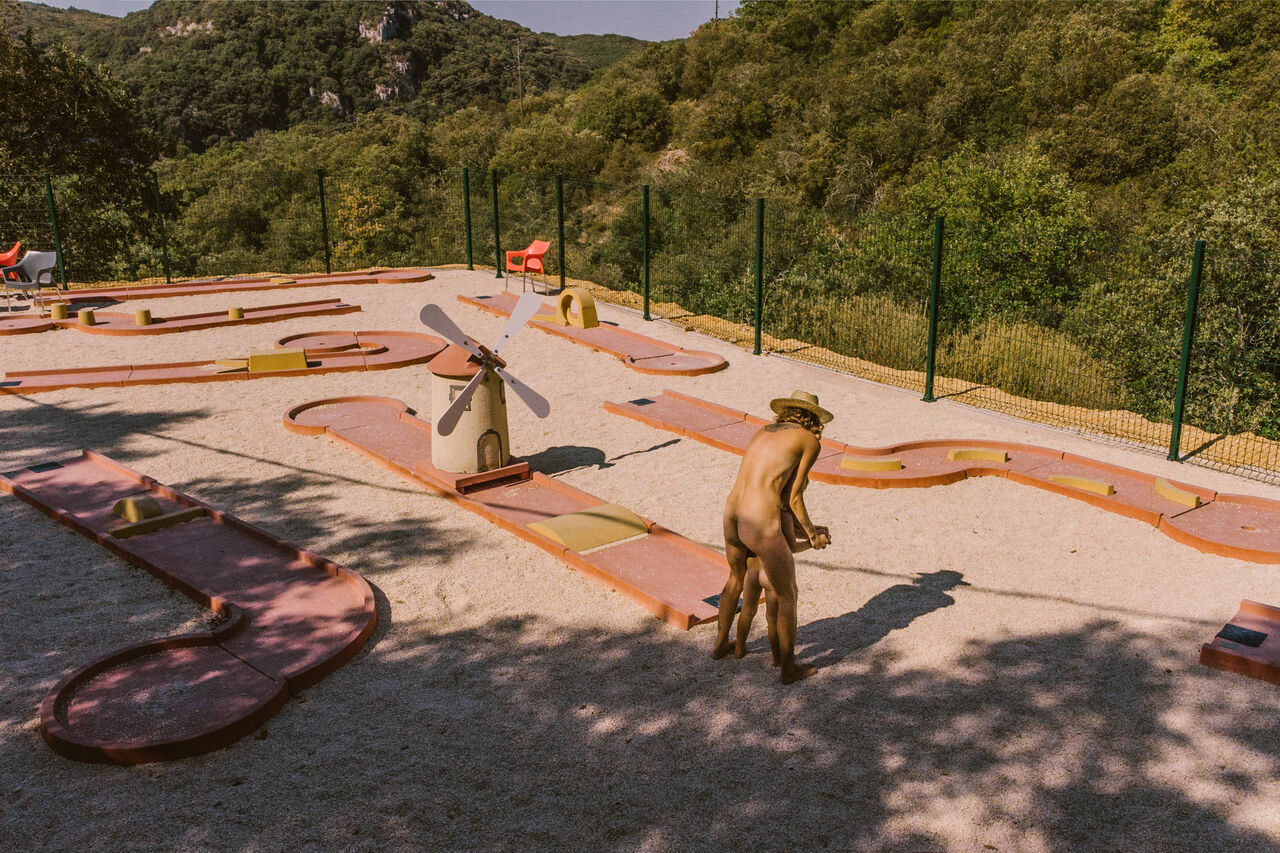 Parcours de mini-golf avec moulin, personne naturiste jouant au camping LIBRANOO Naturiste Sabliere � Barjac (30).